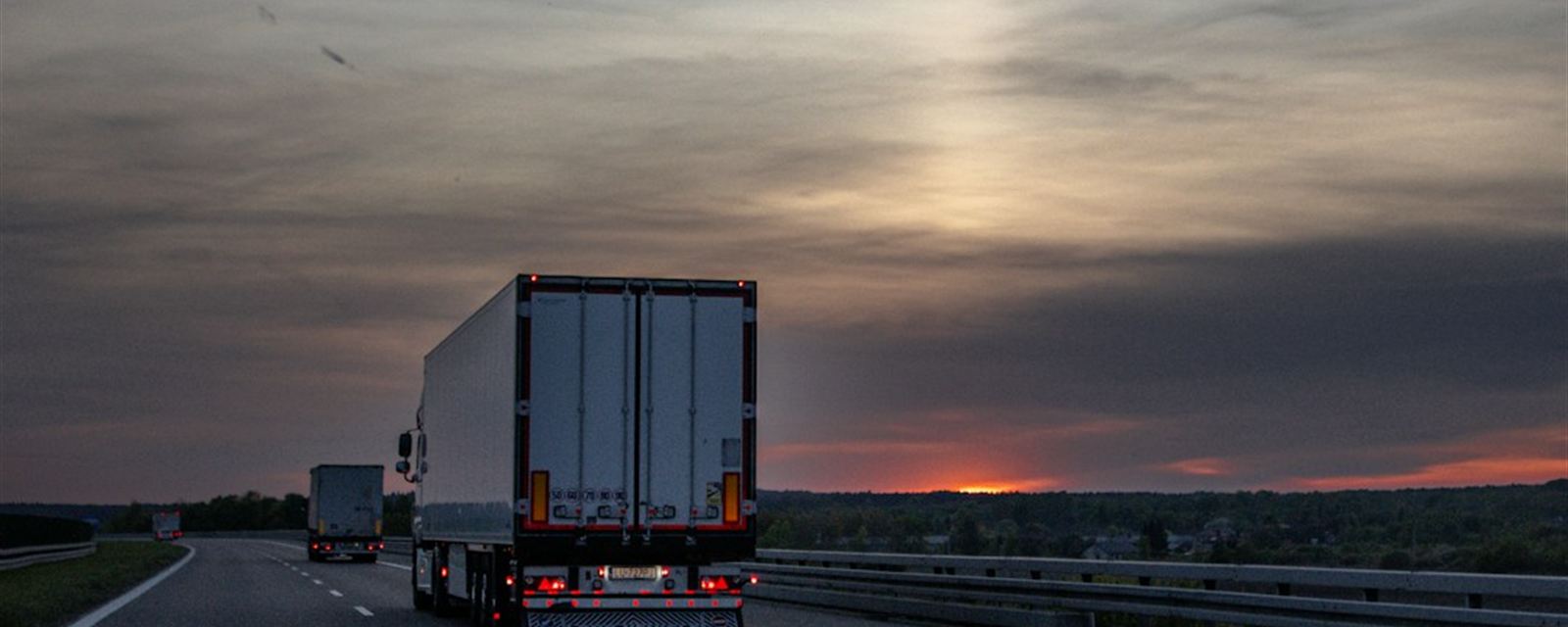 Freight trucks under a sunset sky — waiting at docks costs drivers money